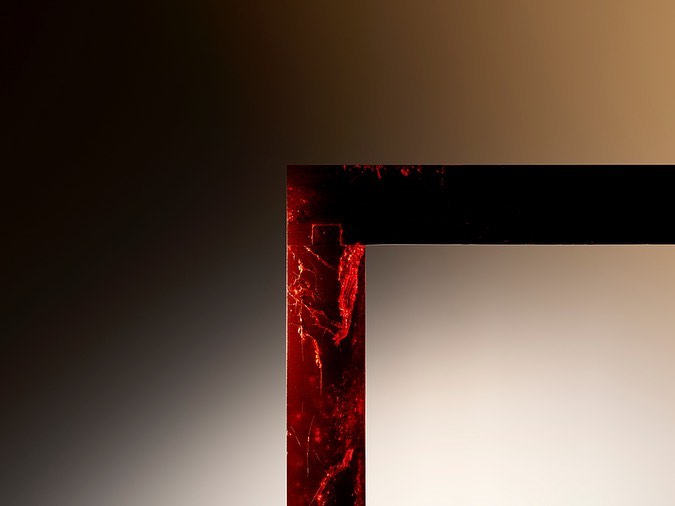 Abstract close-up of a dark rectangular frame with a cracked red texture against a gradient brown background, showcasing modern design.