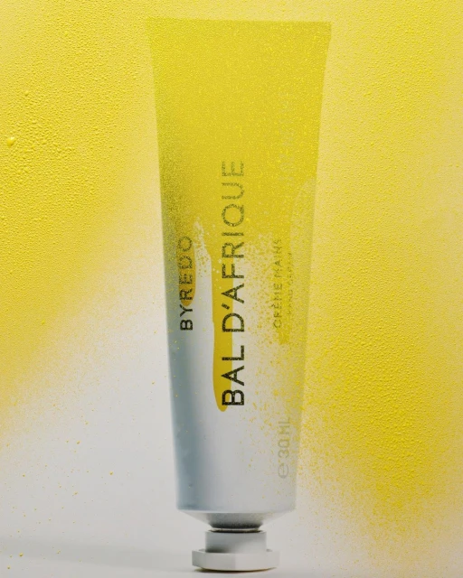 BYREDO BAL D'AFRIQUE hand cream tube with yellow color gradient against a light yellow background in a studio shot.