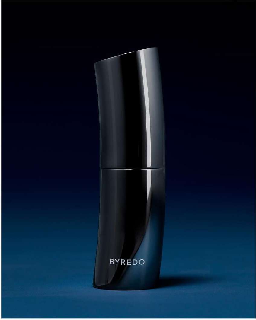 Byredo perfume bottle in studio lighting against a gradient blue background. The sleek, curved bottle reflects light.