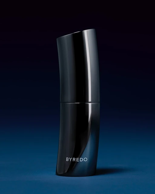Sleek, curved dark gray perfume bottle by Byredo on a dark blue surface with subtle reflections, minimal modern product shot, beauty.