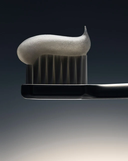Macro shot of a toothbrush with white toothpaste on top, set against a dark gradient background showcasing dental hygiene