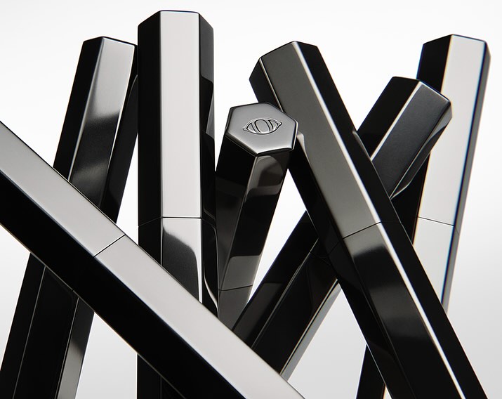 Abstract composition featuring several black, hexagonal cosmetic tubes arranged in a visually striking, geometric pattern on a white background.