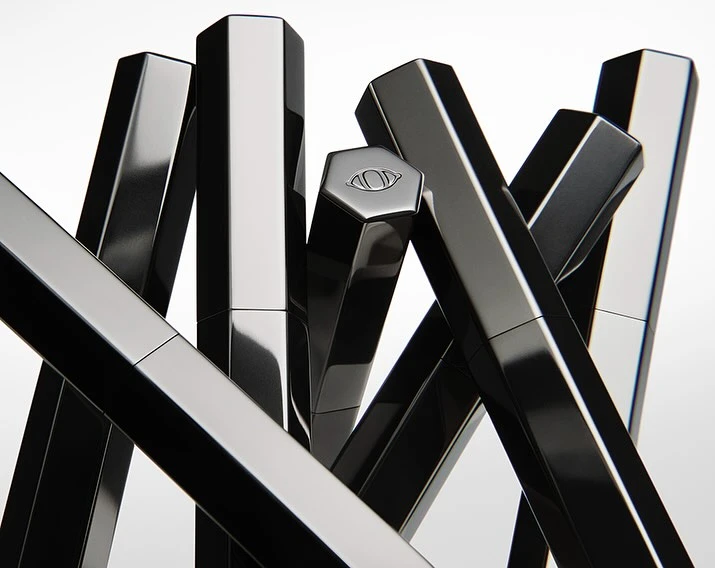 Abstract composition featuring several black, hexagonal cosmetic tubes arranged in a visually striking, geometric pattern on a white background.