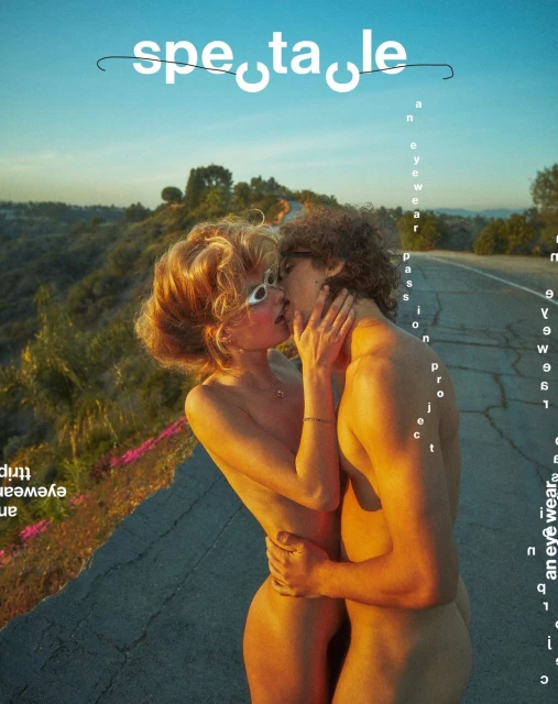 Topless couple kissing on a road at daytime in warm light. The female model wears eyewear. Image is a magazine cover.