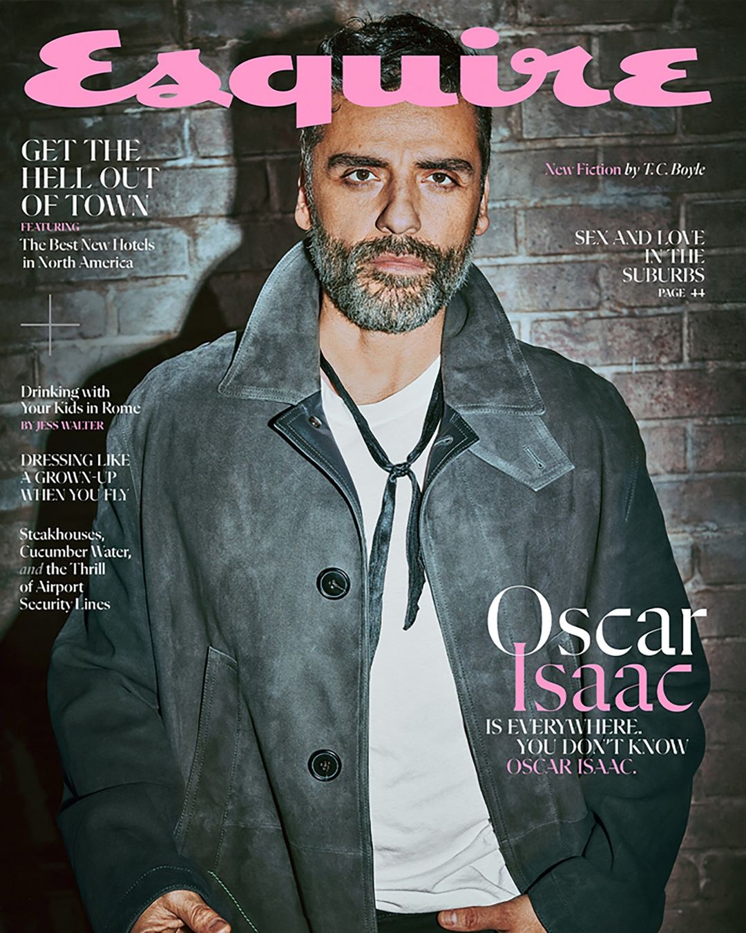 Esquire magazine cover featuring Oscar Isaac in a stylish coat, set against a brick background. The cover includes various headlines and text.