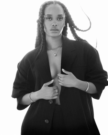 Black and white portrait of a woman wearing an oversized blazer with long braided hair against a white background