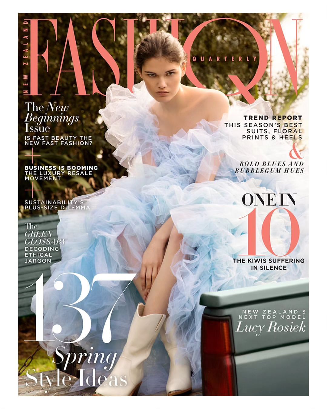 Fashion magazine cover featuring a woman in a light blue dress and white boots sitting near a green vehicle outdoors.