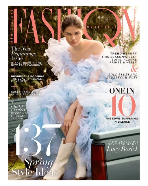 Fashion magazine cover featuring a woman in a light blue dress and white boots sitting near a green vehicle outdoors.