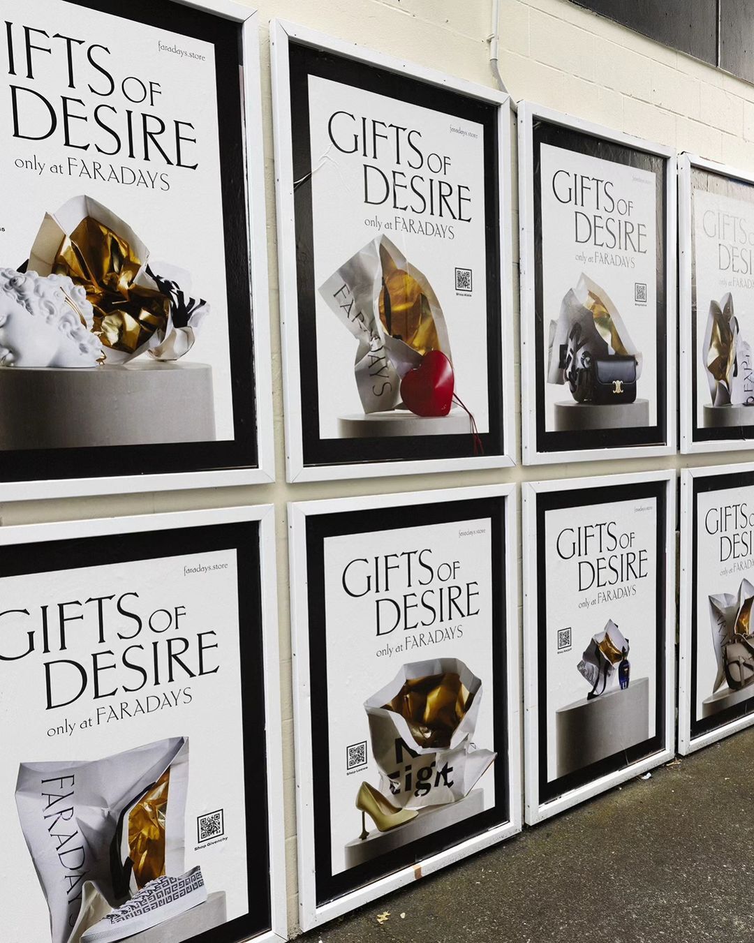 Several framed posters reading 'Gifts of Desire only at Faradays' hang on a wall, each featuring different luxury goods in shopping bags.