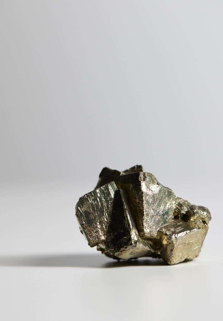 Detailed studio shot of a pyrite mineral specimen featuring metallic luster and crystalline structure against a gradient background.