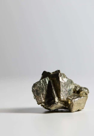 Detailed studio shot of a pyrite mineral specimen featuring metallic luster and crystalline structure against a gradient background.
