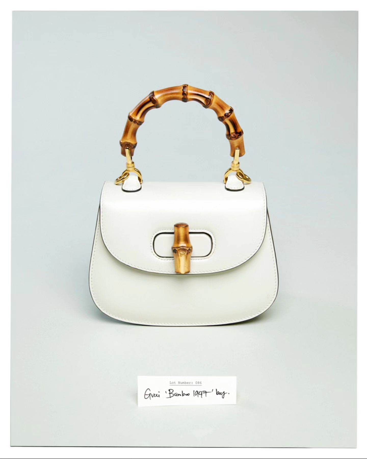 Elegant white leather Gucci Bamboo 1947 handbag featuring a distinctive bamboo handle, displayed in a product shot against a pale gray background.