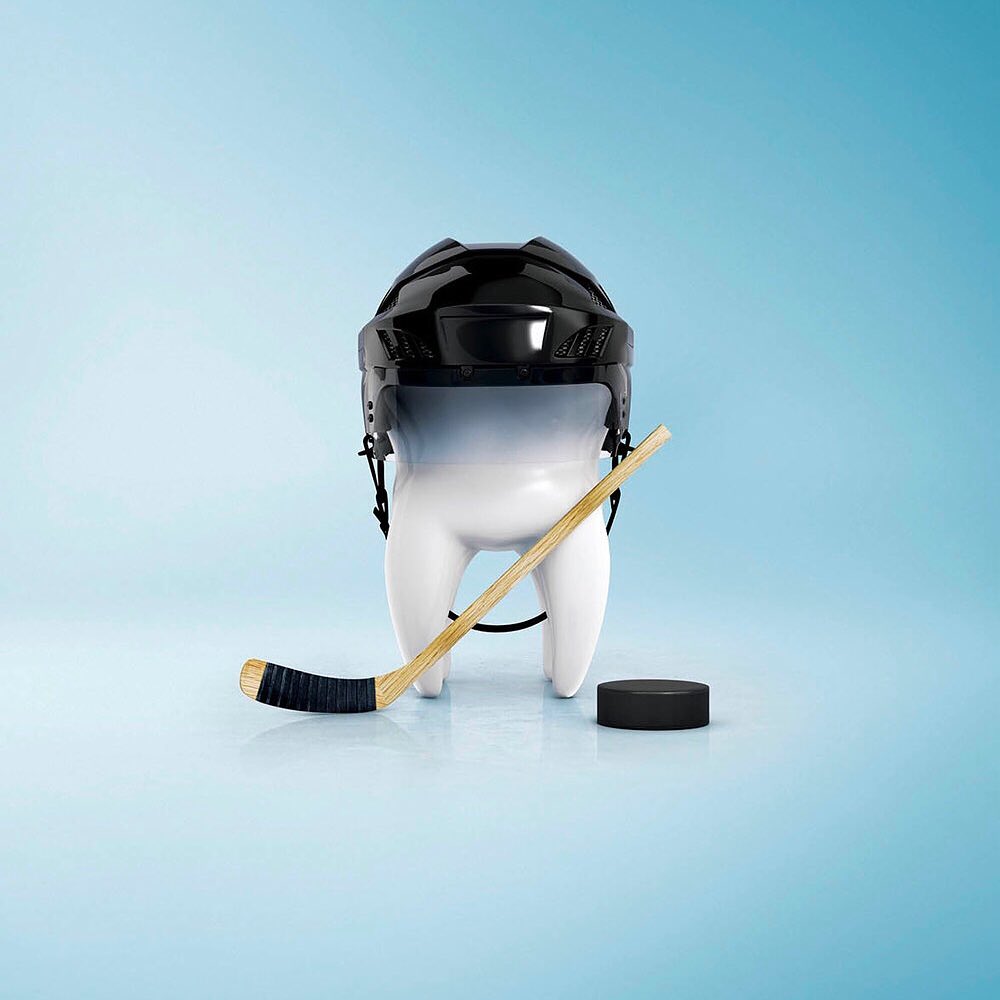 Conceptual dental health image: A tooth wears a hockey helmet and is posed with a hockey stick and puck against a gradient blue background.