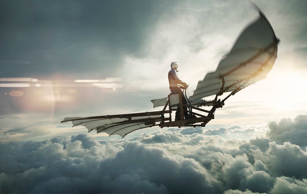 An imaginative scene showing a man piloting a Da Vinci-style flying machine amidst a cloudy sky with the sun creating a lens flare.