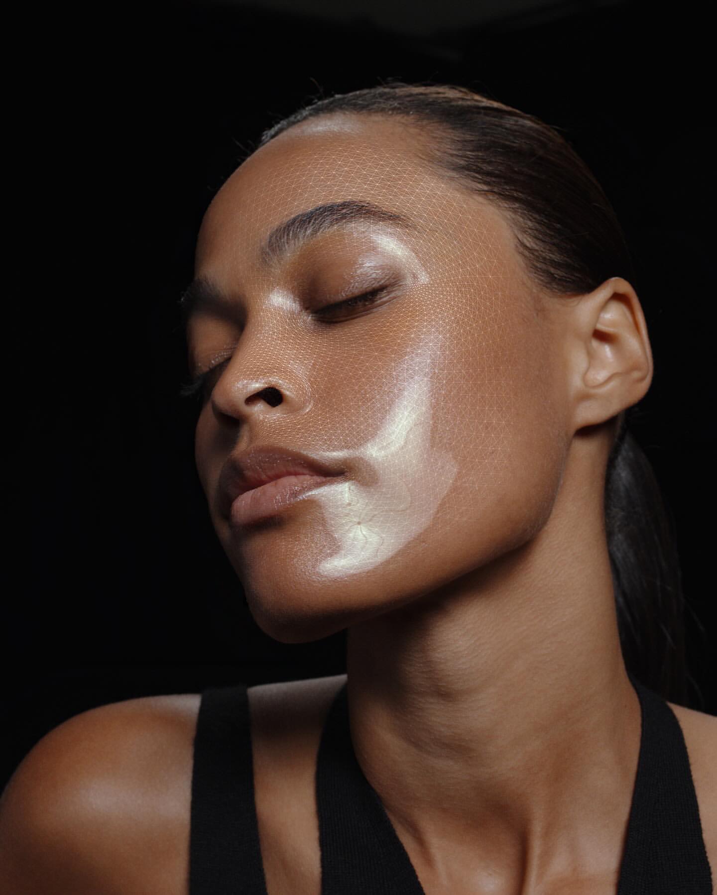 Close-up portrait of a woman with glowing skin and closed eyes against a dark background, photographed by Hai Ngo