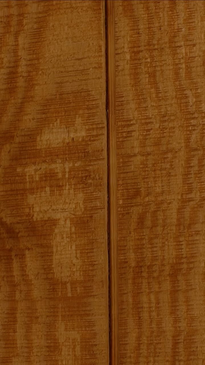 Close-up of wood texture featuring a linear grain pattern in warm amber tones with a distinctive vertical center seam.