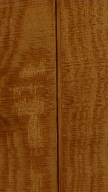 Close-up of wood texture featuring a linear grain pattern in warm amber tones with a distinctive vertical center seam.