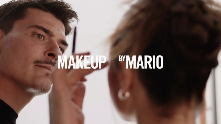 Makeup artist applying makeup to a model in a brightly lit studio, featuring close-up shot and 'Makeup by Mario' text overlay.