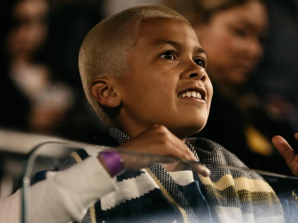 Young child with short blonde hair and striped scarf looking upward smiling, photographed by Hana Asano in New York.