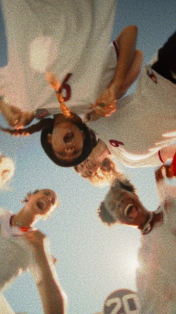 Low-angle shot of a group of cheering athletes in uniform with number 6 on their shirts against a clear blue sky.