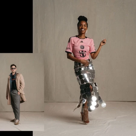 Woman in pink soccer jersey and silver skirt posing in a studio with a man in a trench coat standing to the side.