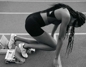 Black athlete in starting blocks wearing sports bra and shorts on a running track captured by Hana Asano in New York