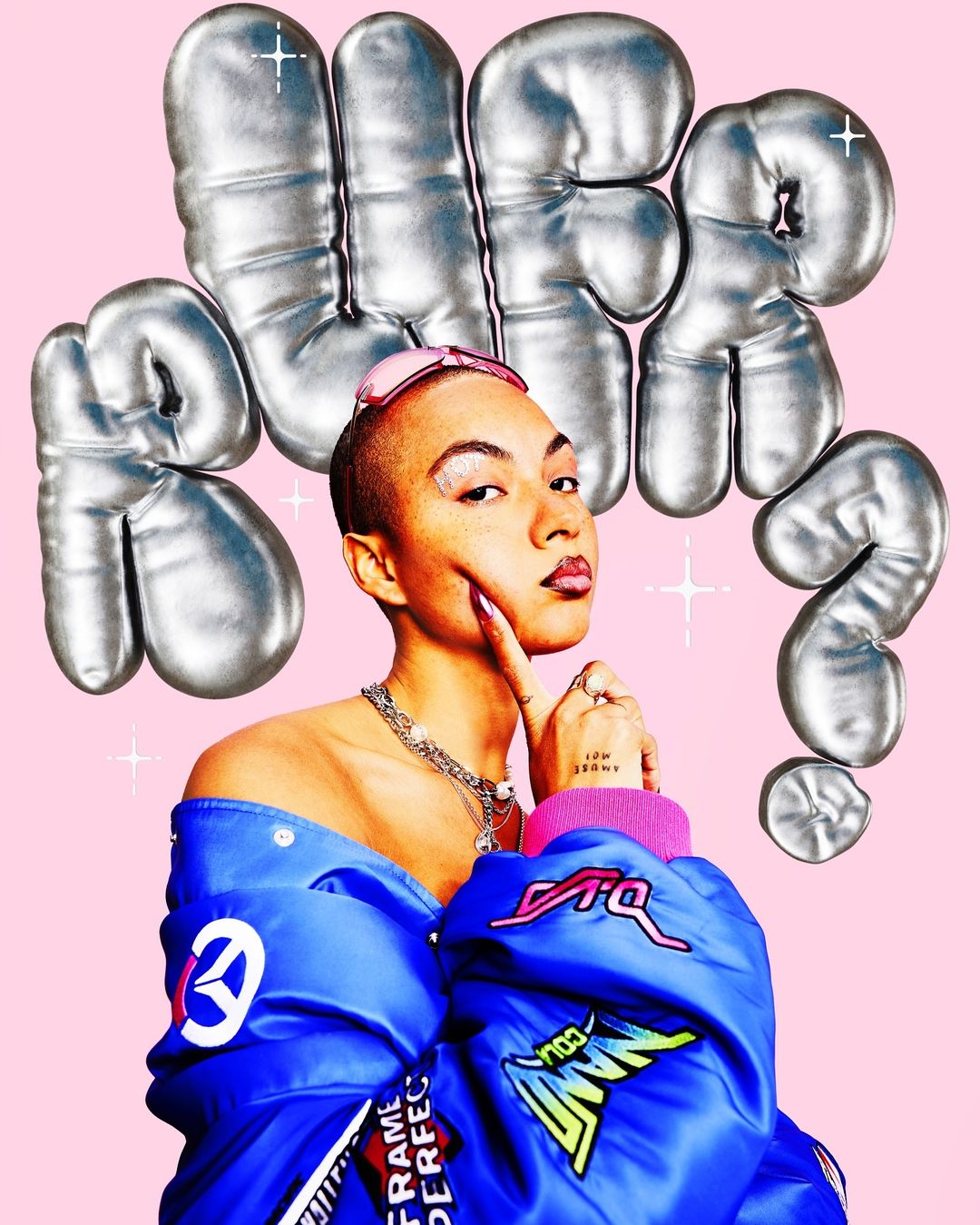 Woman in blue jacket poses with silver balloon letters on pink backdrop, showcasing fashion, makeup, and edgy style.