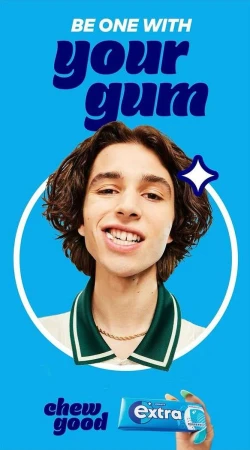 Close-up studio shot of a young adult male smiling with a pack of Extra gum in his hand on a bright blue background.