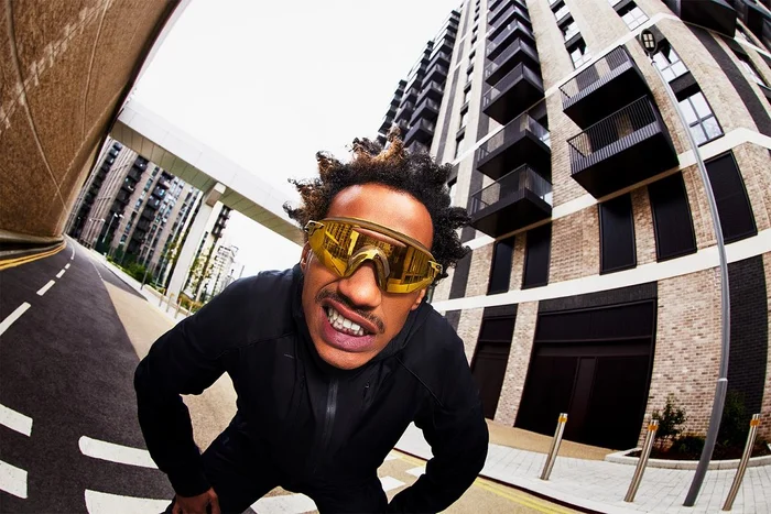 Man wearing mirrored sunglasses and a black zip jacket outdoors in London captured with wide angle lens by Hanina.
