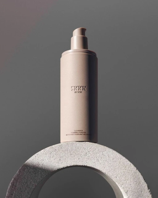 SKKN by Kim product shot: a skincare bottle displayed on a textured ring against a gray background with soft, diffused lighting.