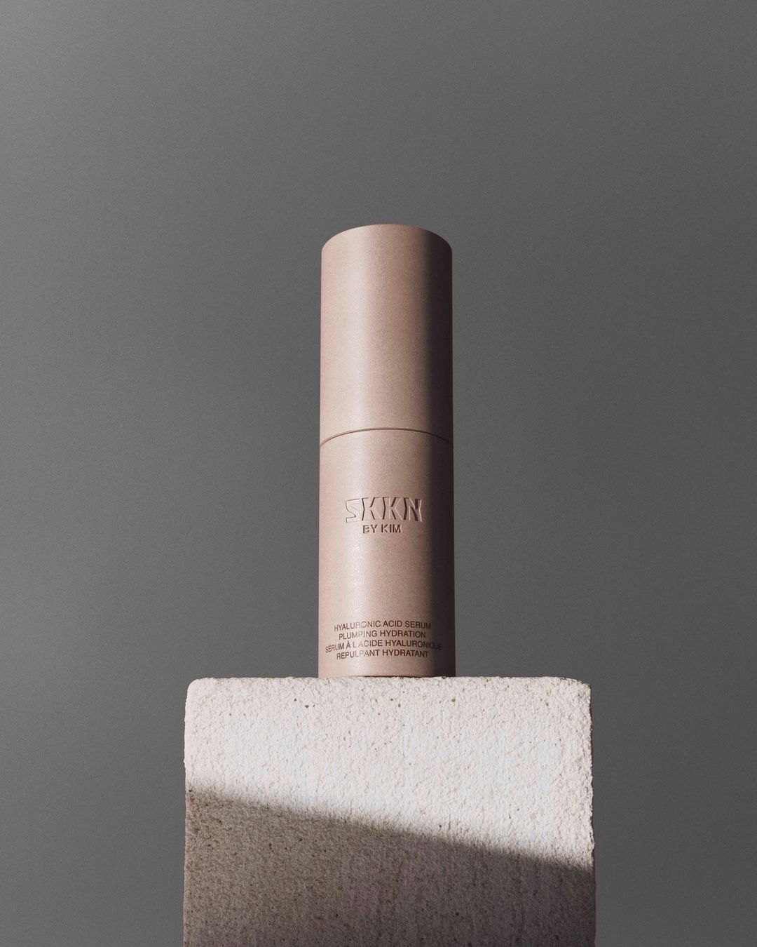 SKKN by Kim Hyaluronic Acid Serum bottle on a white block against a grey background, product shot for beauty and skincare.