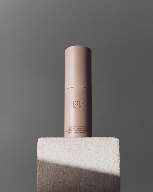 SKKN by Kim Hyaluronic Acid Serum bottle on a white block against a grey background, product shot for beauty and skincare.