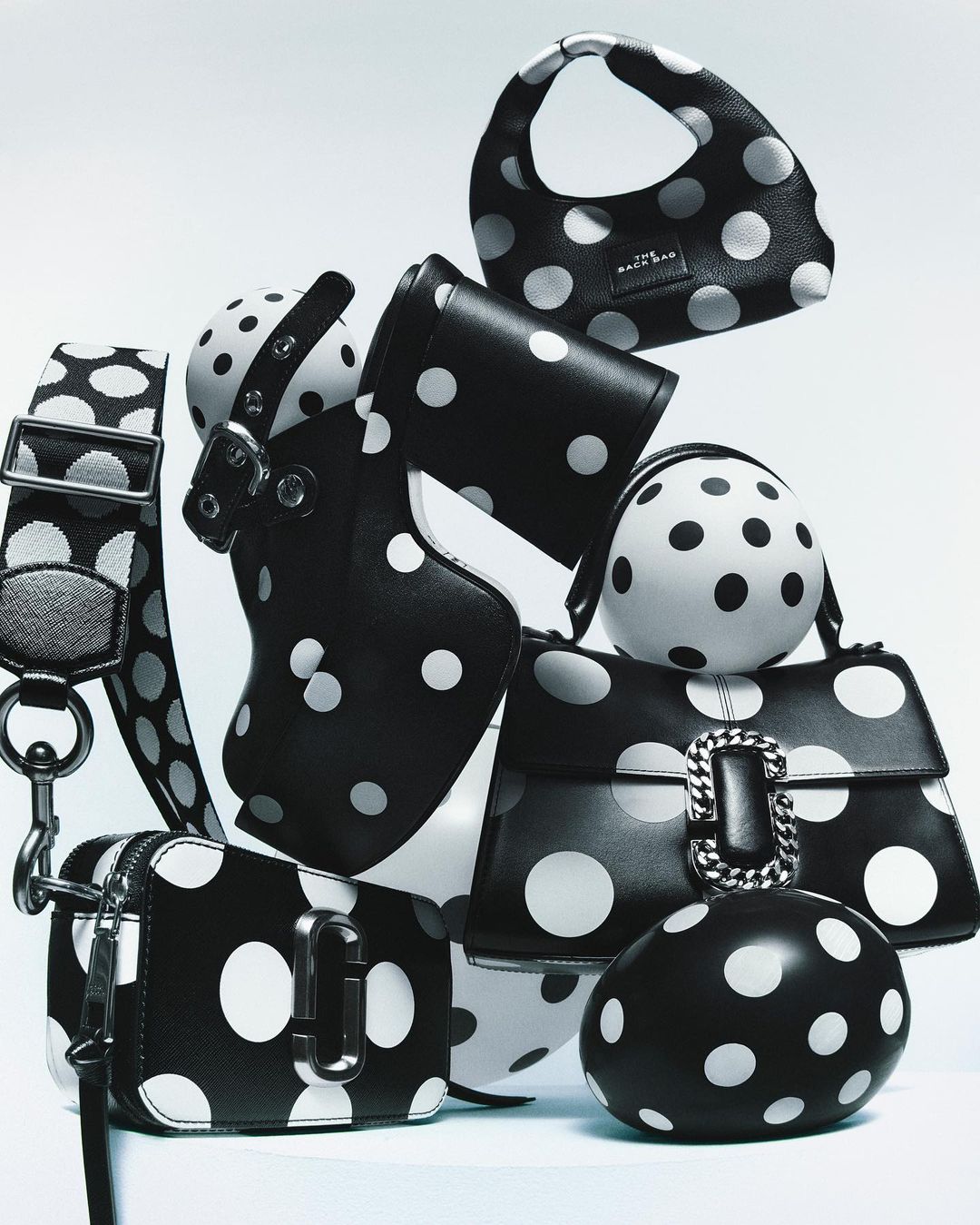 Collection of stylish black purses and accessories adorned with white polka dots, arranged on a white surface in a studio setting.