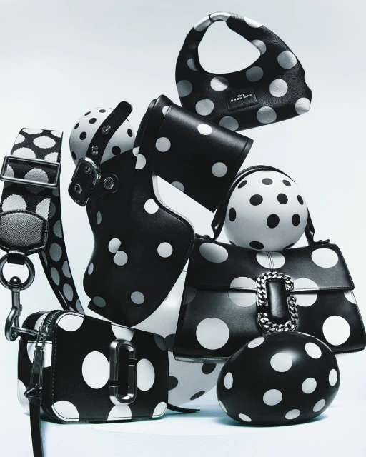Collection of stylish black purses and accessories adorned with white polka dots, arranged on a white surface in a studio setting.