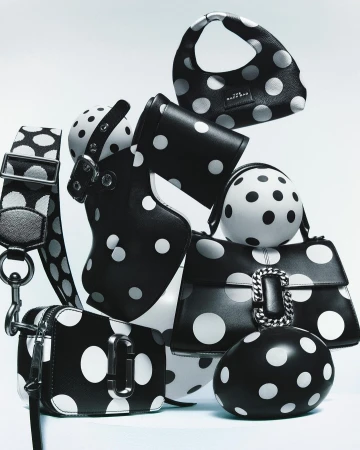 Collection of stylish black purses and accessories adorned with white polka dots, arranged on a white surface in a studio setting.