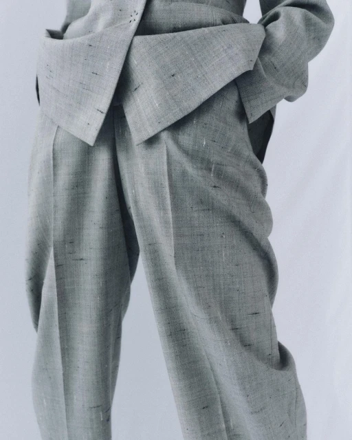 Grey textured suit with structured design and straight leg pants. The suit is presented on a white backdrop, focusing on fabric details.