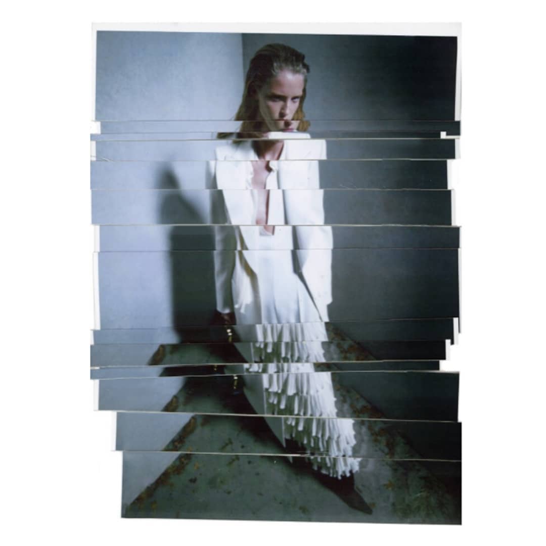 A woman poses in a white jacket and skirt with fringe details, the image constructed from horizontally sliced photographs on a white background.