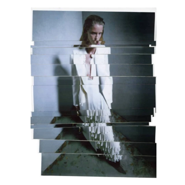 A woman poses in a white jacket and skirt with fringe details, the image constructed from horizontally sliced photographs on a white background.