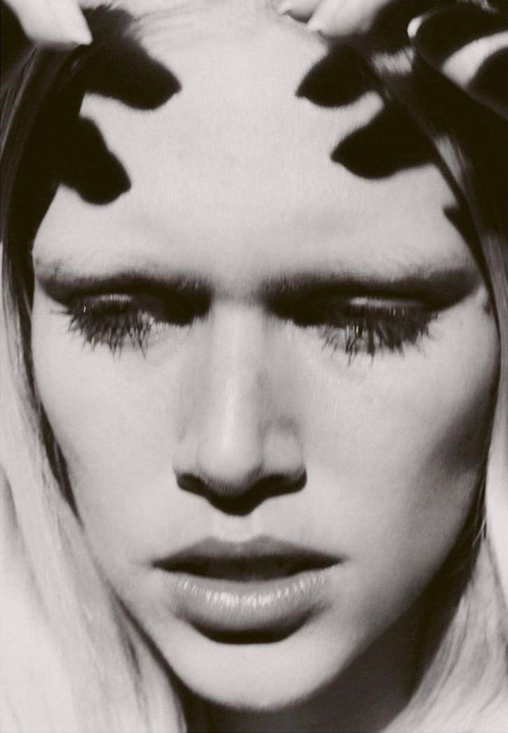 Close up portrait of a woman with dramatic black shadows cast across her forehead by fingers, photographed by Hanna Tveite.