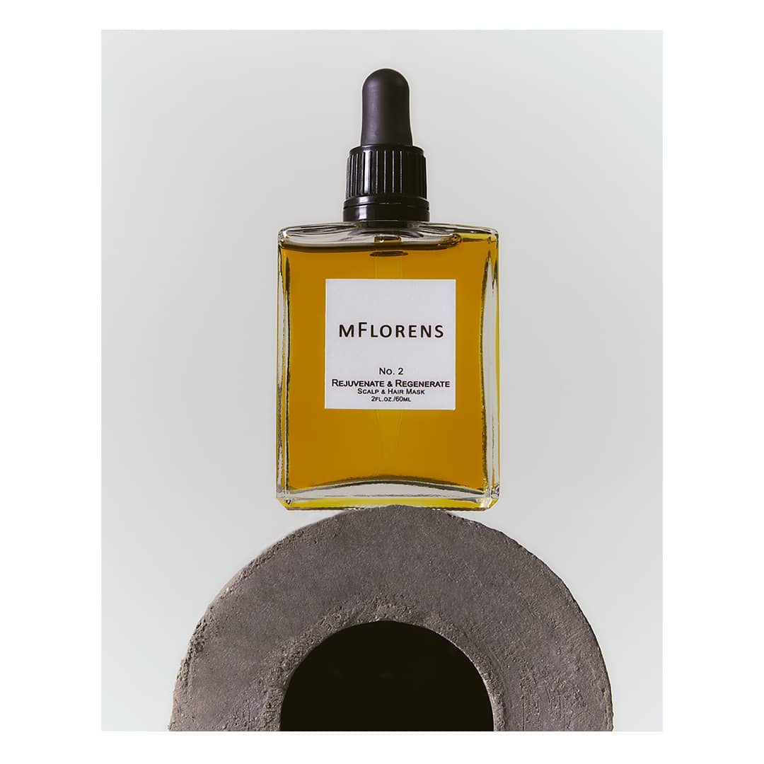 Cosmetic bottle with a dropper on a grey stone base against a white backdrop, product shot for beauty and wellness, neutral color palette.