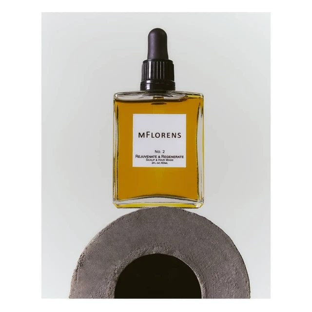 Cosmetic bottle with a dropper on a grey stone base against a white backdrop, product shot for beauty and wellness, neutral color palette.