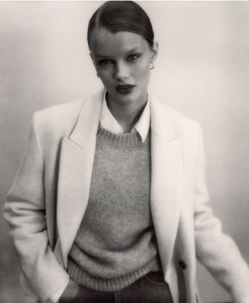 A black and white portrait of an adult woman in a light-colored blazer over a sweater and button-down shirt, posing against a neutral backdrop.