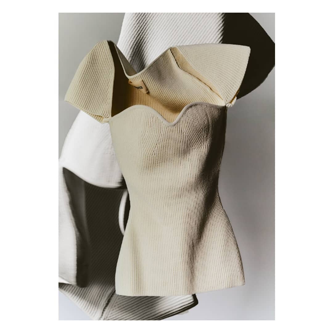 Elegant ivory-colored ribbed knit top with a sweetheart neckline and ruffled sleeves, captured in a high-key fashion photograph.
