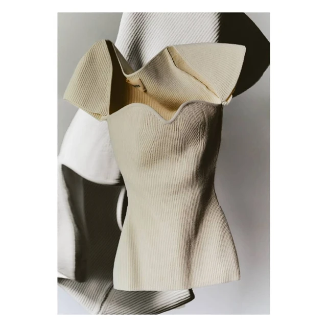 Elegant ivory-colored ribbed knit top with a sweetheart neckline and ruffled sleeves, captured in a high-key fashion photograph.