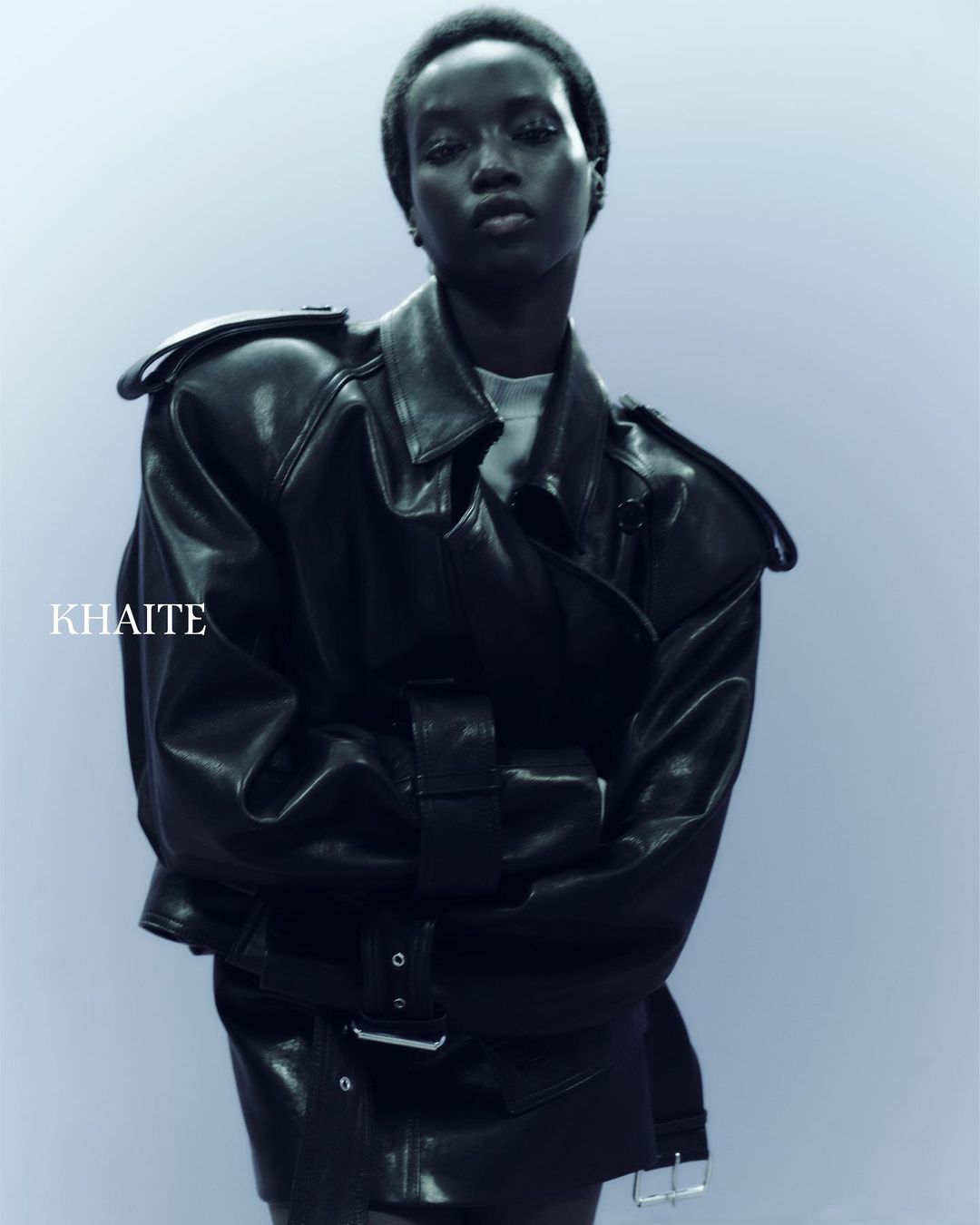 Close-up shot of an African American female model wearing a black leather jacket. Fashion shot with a plain backdrop, studio lighting.