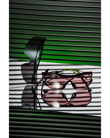 Two pairs of sunglasses are arranged in front of a horizontally striped background, casting shadows. One pair is stacked on the other.