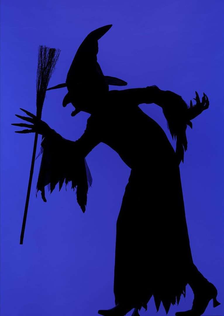 Silhouette of a person in a witch costume with a hat and broom on a blue background, dark, mysterious, Halloween vibe.