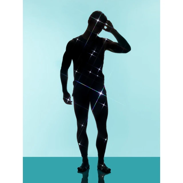 Silhouette of a male figure standing in front of a light blue background with a teal-colored reflective floor surface, sparkling effect.