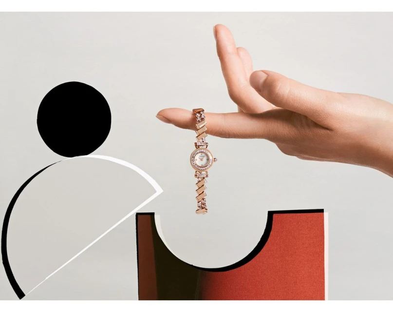 Elegant wrist watch on fingertip with minimalist geometric backdrop. Sophisticated fashion accessory in a modern, stylized product display.