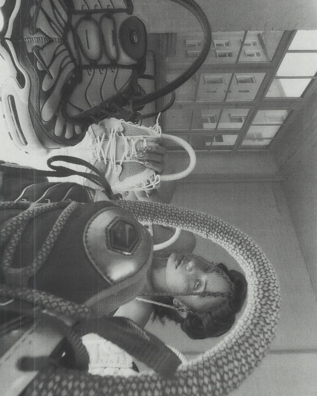 Monochrome studio shot of a woman with a soccer ball, sneakers, and athletic gear, creating an upside-down, surreal composition with natural light.